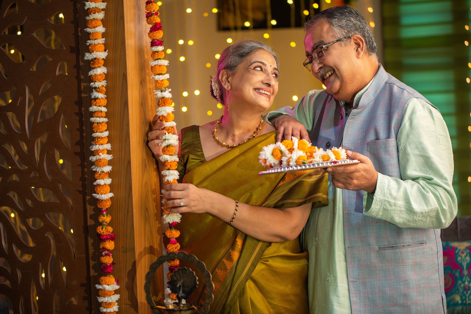 Senior couple hanging floral garlands at entrance during Diwali festival