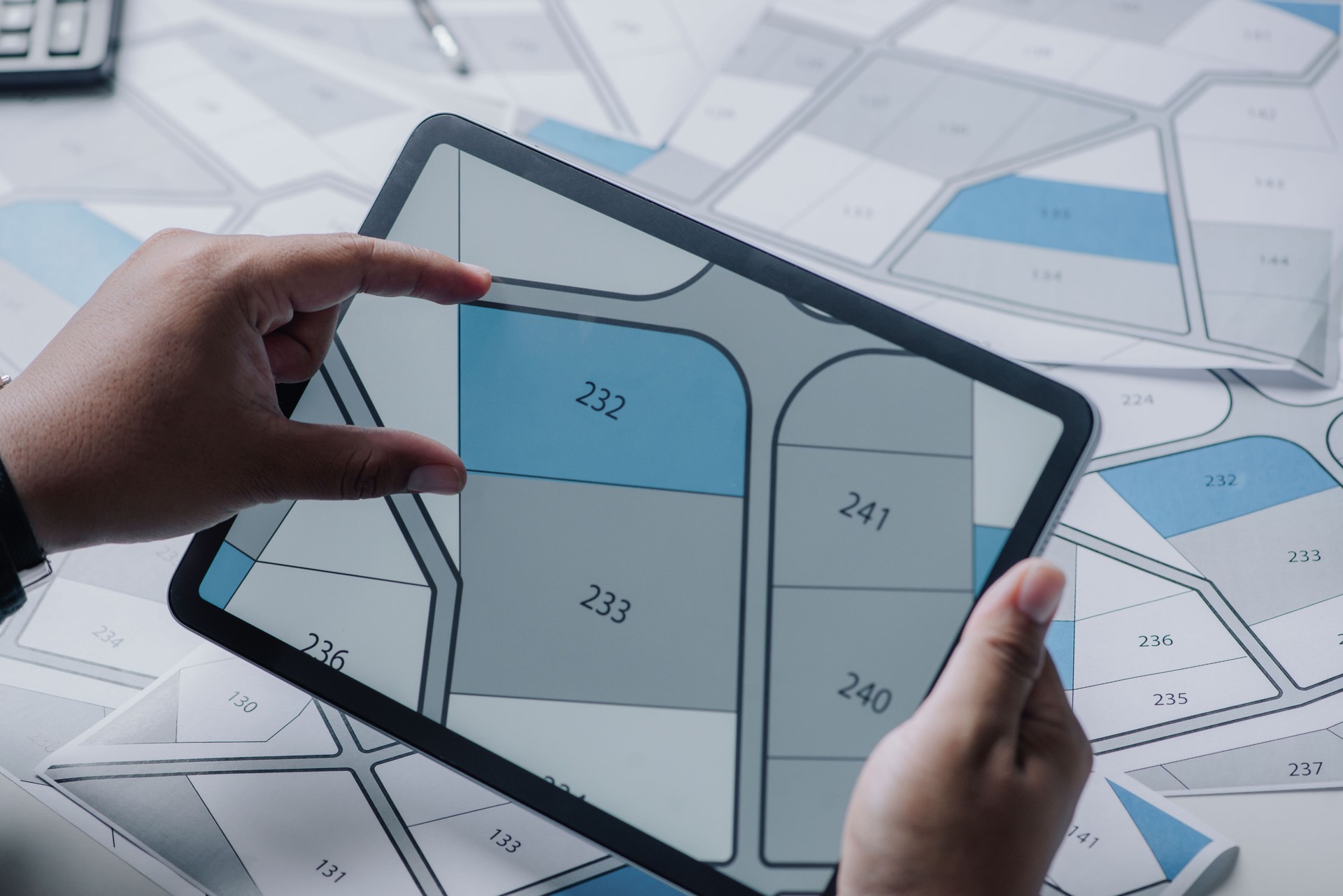 Man searching building plot to buy on cadastral plan for house construction on digital tablet. house or residential i.e. construction, development, sale, buy.