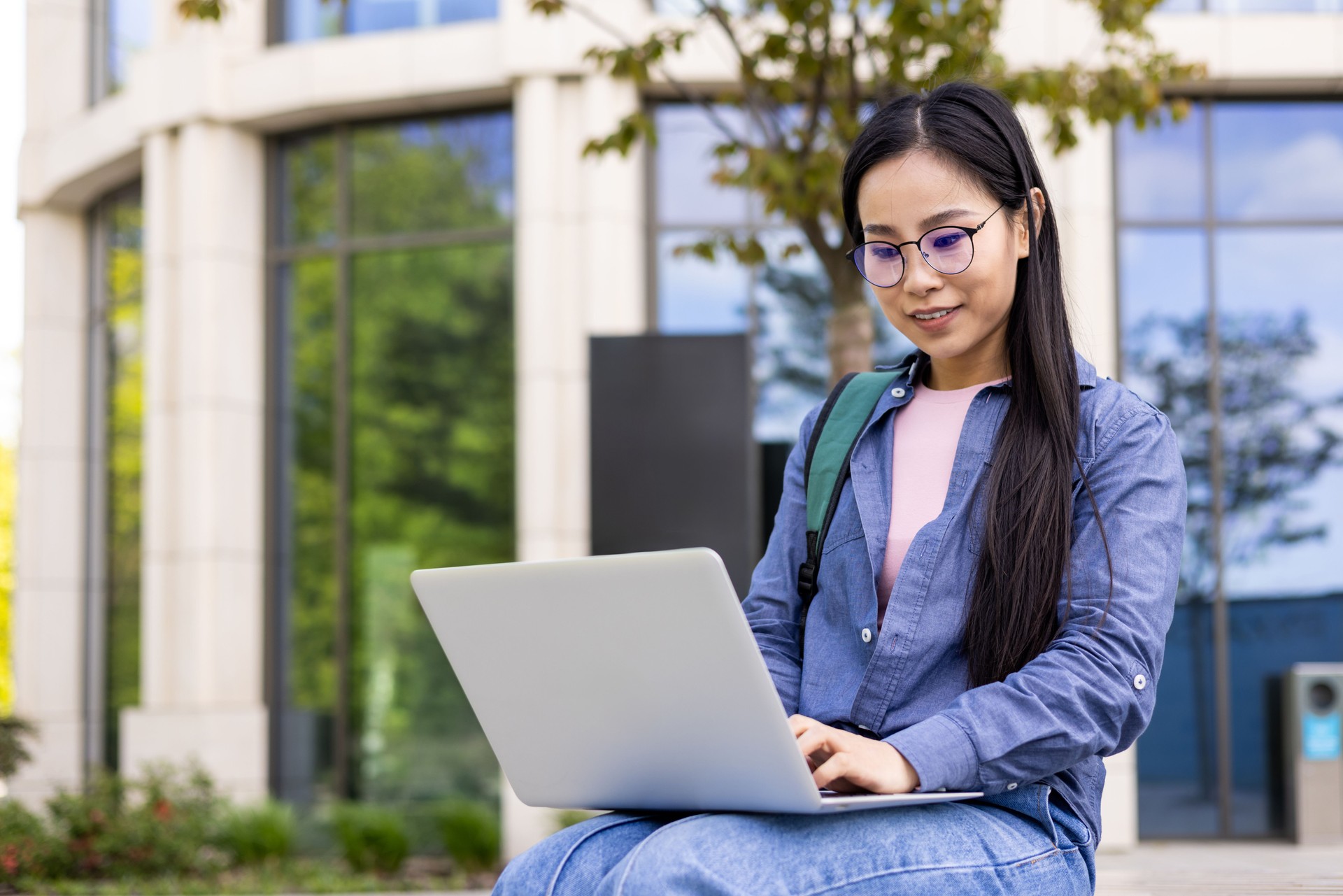 Asian woman using a laptop while working outside on a sunny day. Asian woman using a laptop while working outside on a sunny day.